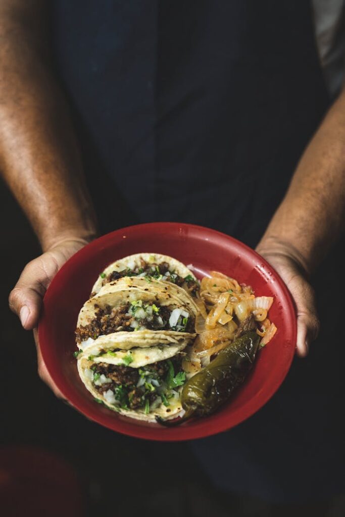 Delicious Mexican street tacos with beef, onions, and jalapenos on a red plate.